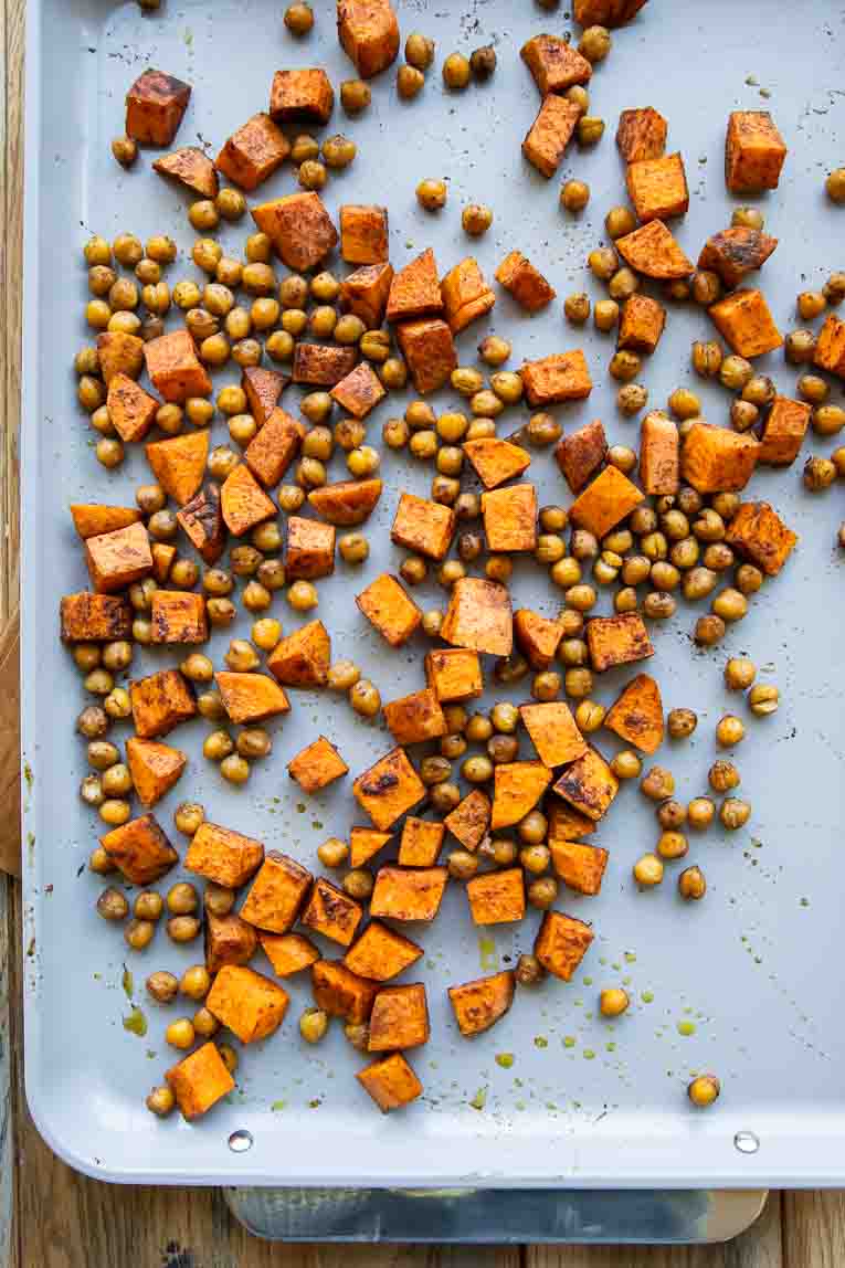 Roasted chickpeas and sweet potatoes on a pan.