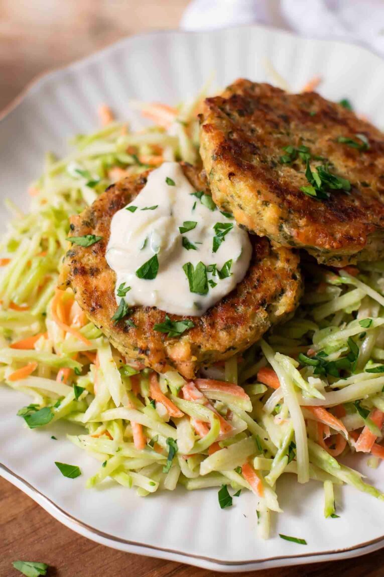 Close up of Salmon Patties over broccoli slaw with yogurt sauce.