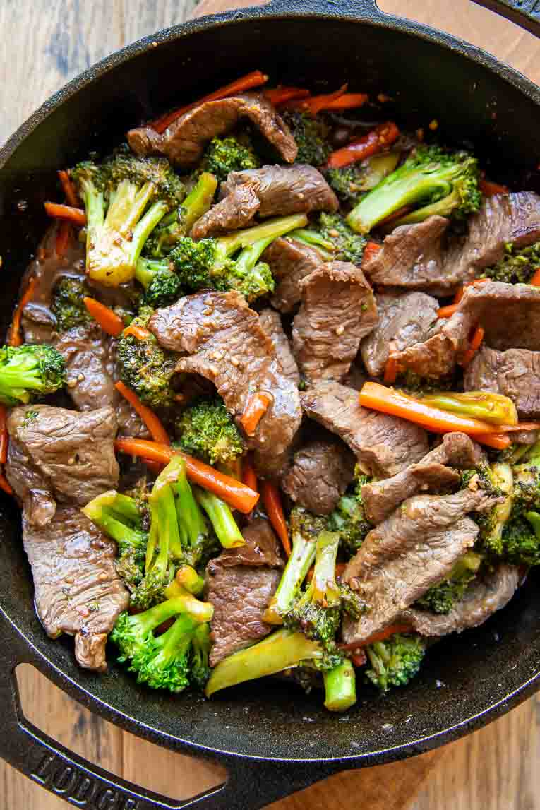 Ginger beef, broccoli, and carrots stir fry in a skillet.