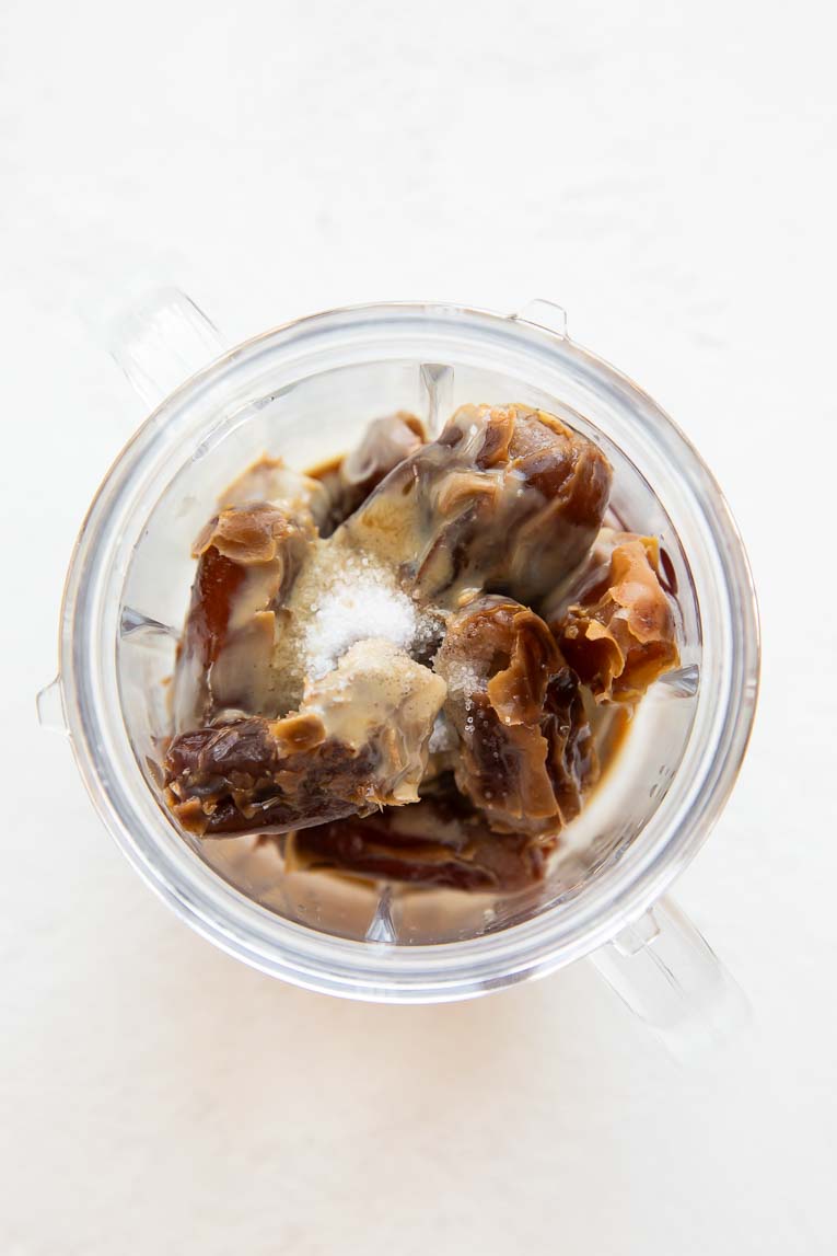 Top shot of dates, tahini, vanilla, and salt in a blender.