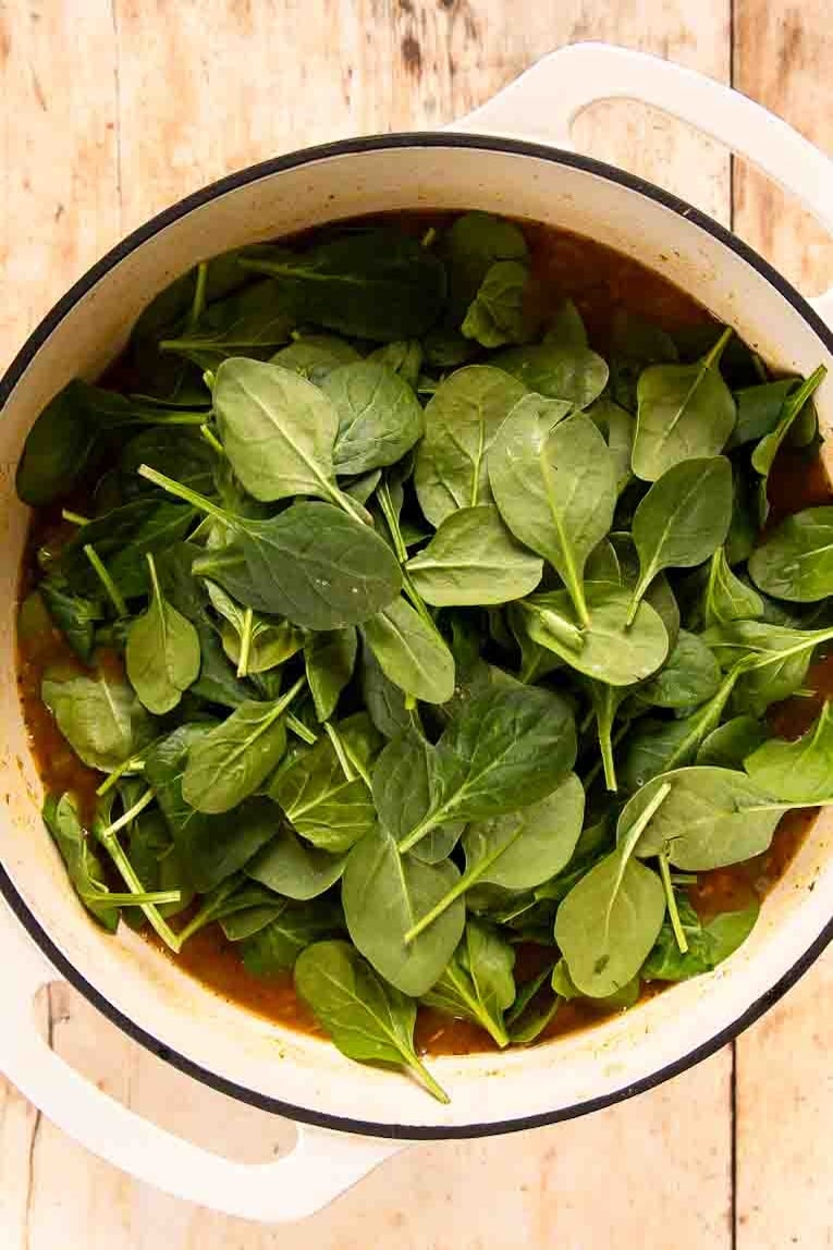 Spinach over lentil soup in a Dutch oven.