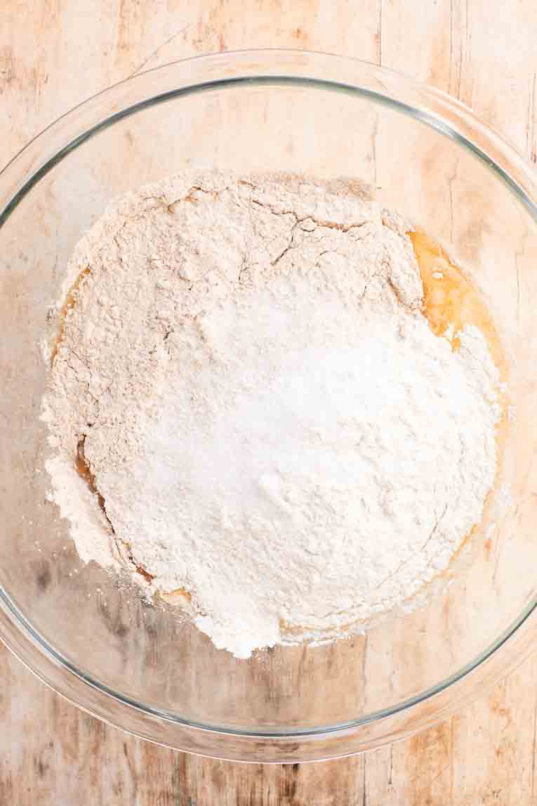 Dry ingredients over active yeast mixture in a bowl.