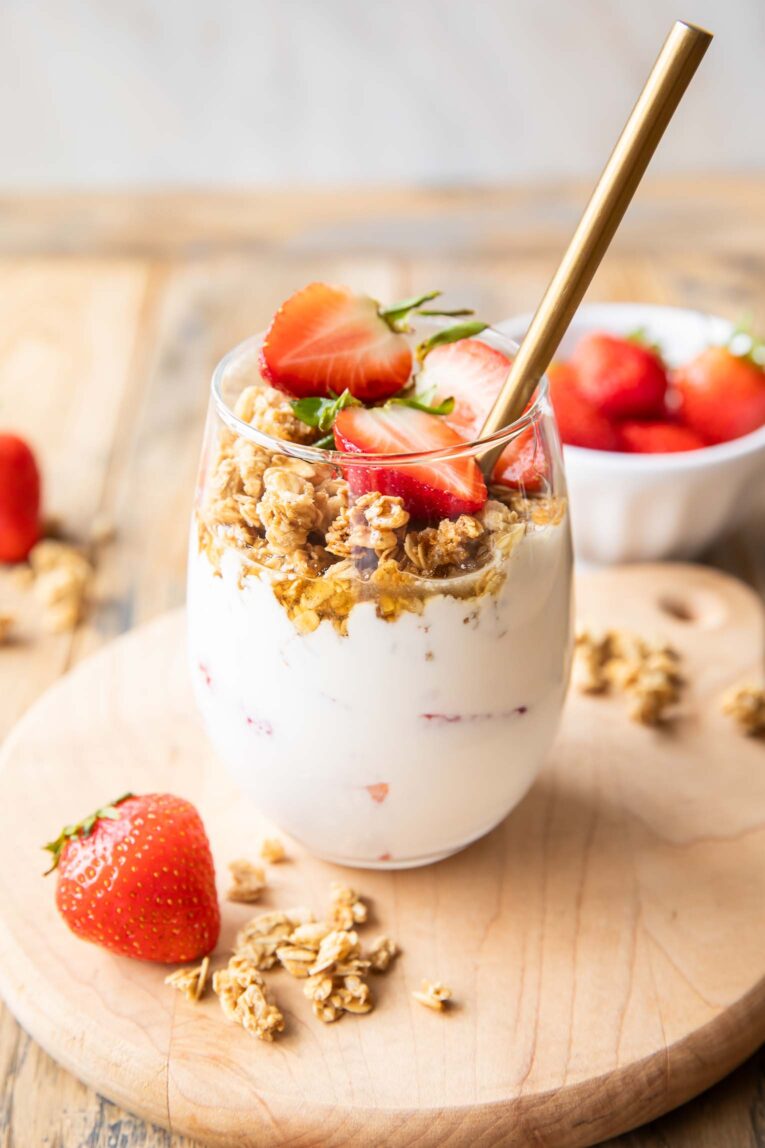 Angled photo of a Strawberry Cheesecake Breakfast Parfait on a cutting board.