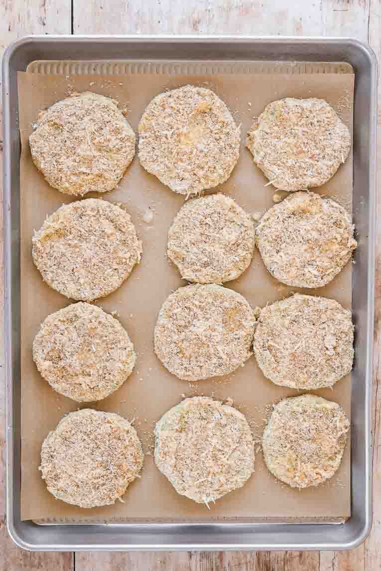 Breaded green tomato slices on a baking sheet.