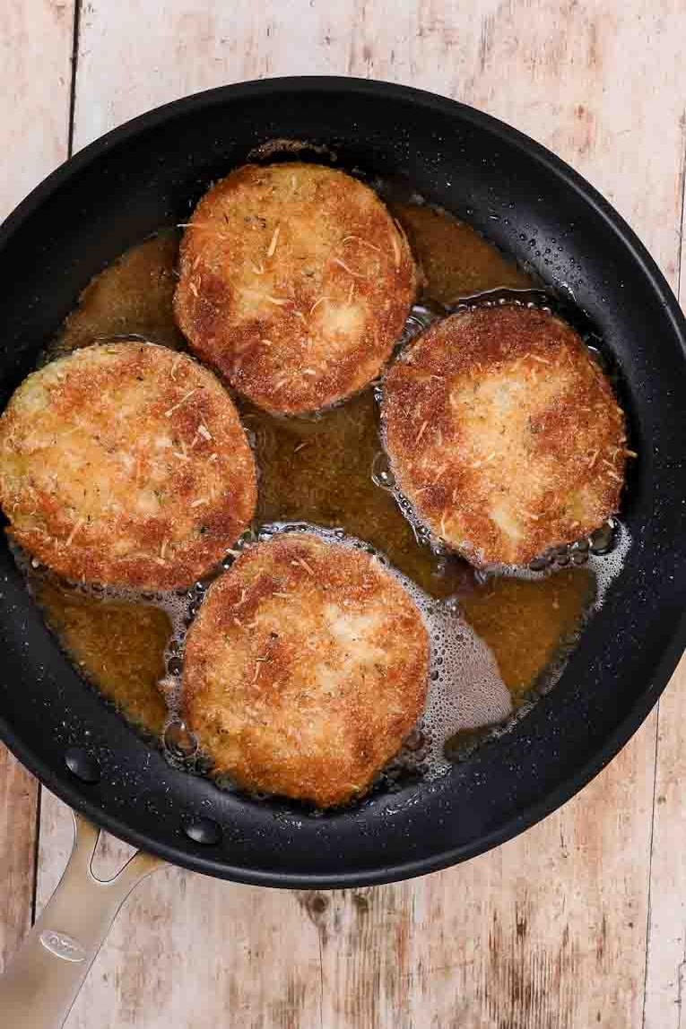 Green tomatoes being fried in a pan.
