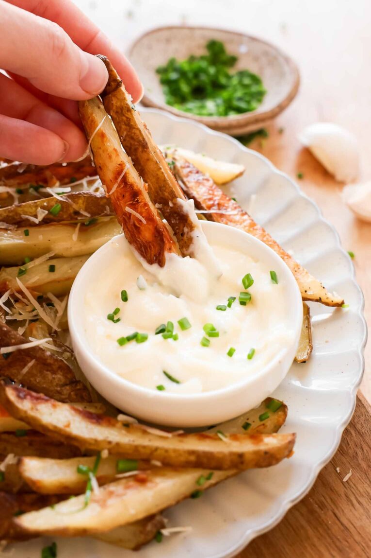 Truffle fries dipping into a mayo garlic sauce.