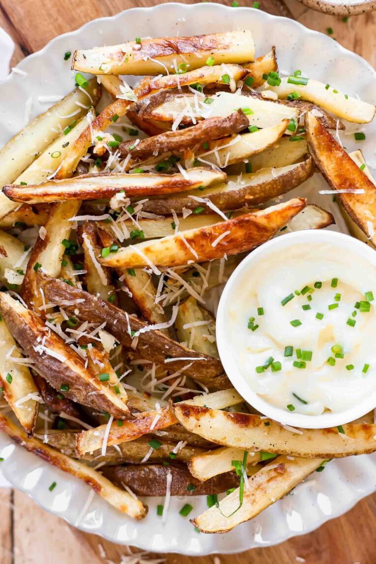 Parmesan truffle fries with garlic aioli on a plate.