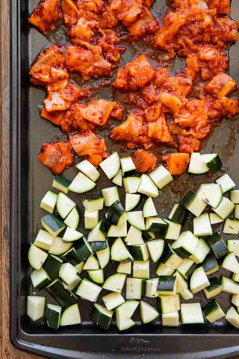 Harissa Salmon with zucchini on a sheet pan with oil.