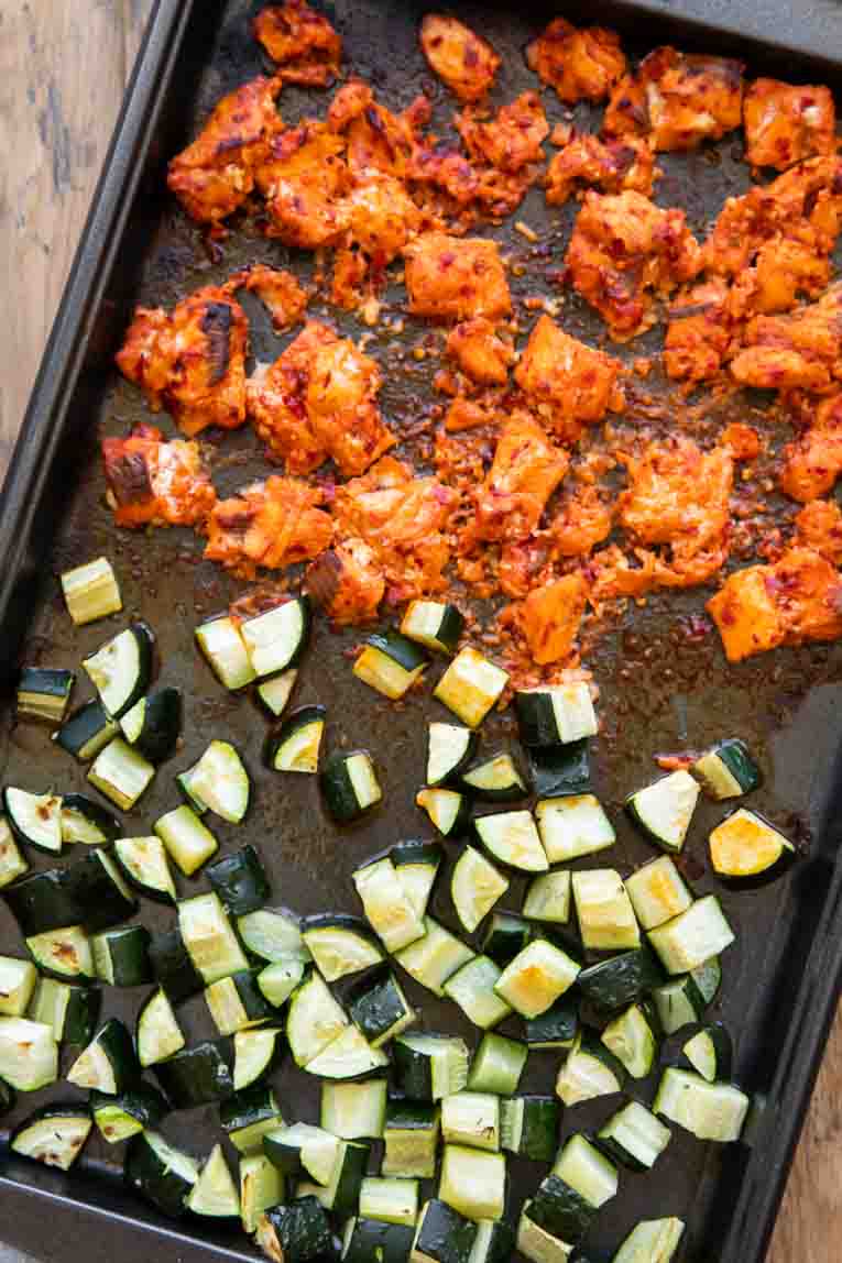 Crispy harissa salmon and roasted zucchini on a sheet pan.