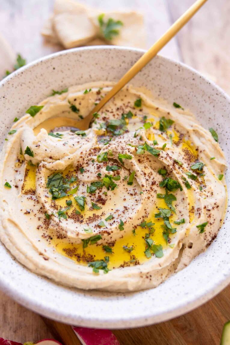 Angled photo of hummus in a bowl with a spoon.