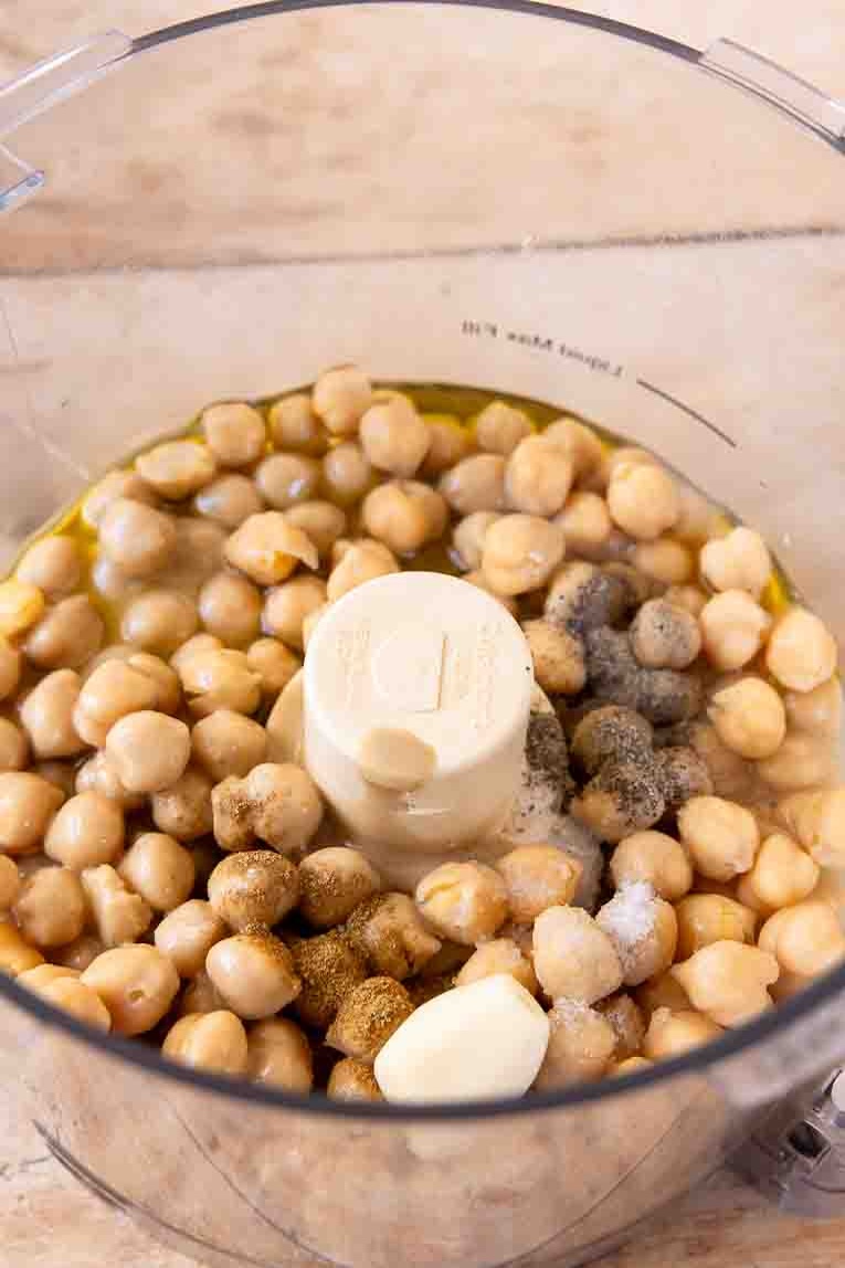 Chickpeas, seasoning, and tahini in a food processor.