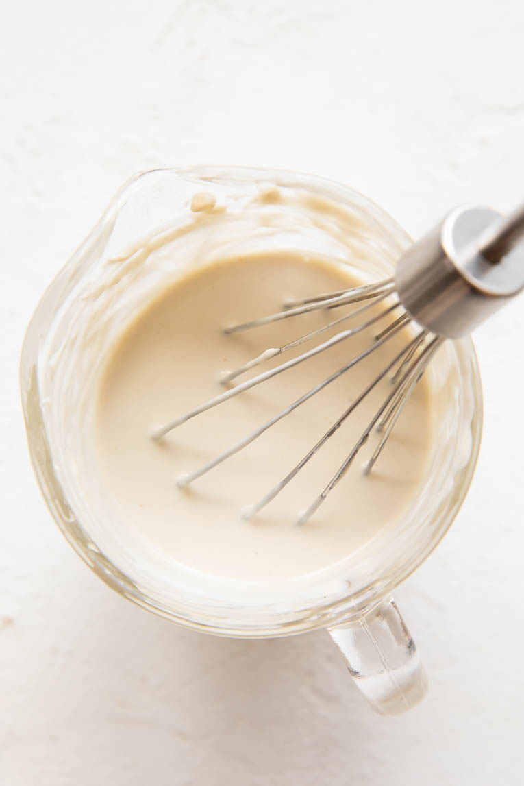 Tahini yogurt sauce being whisked.
