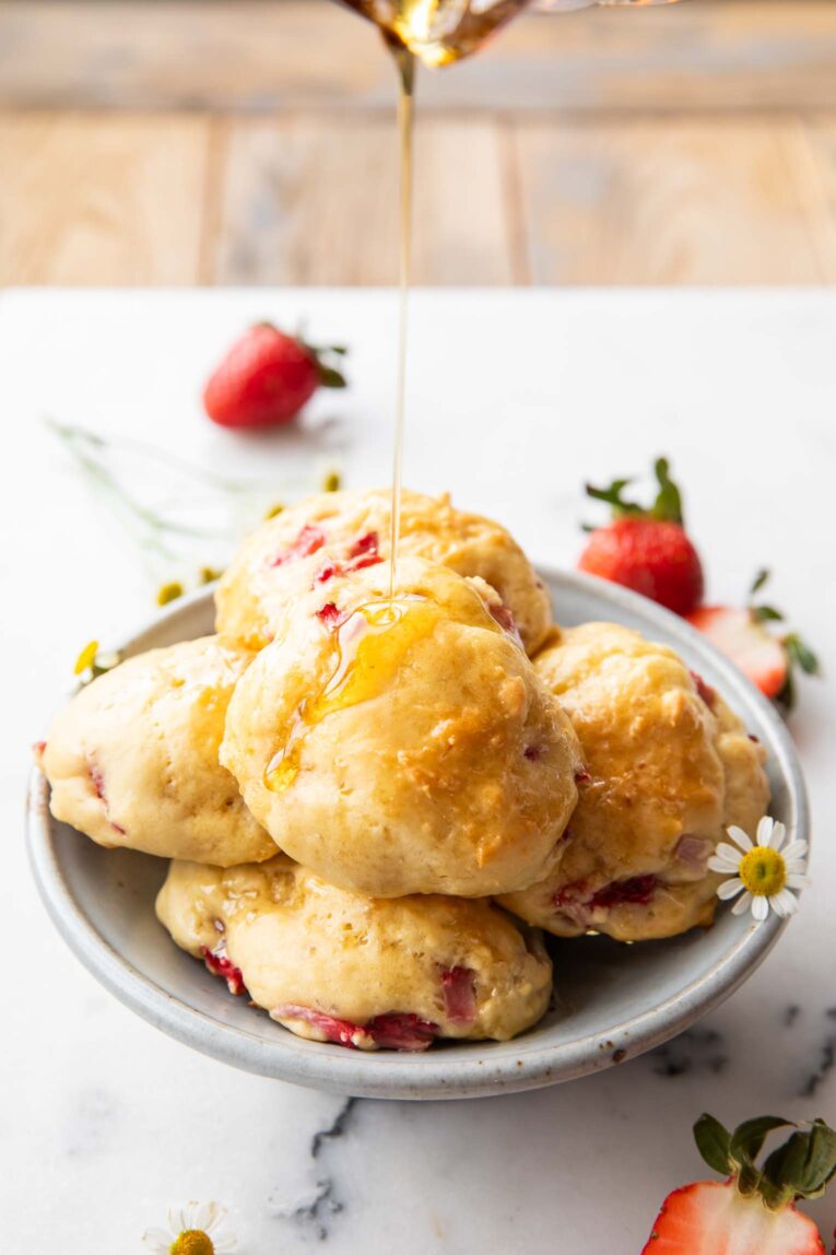 Strawberry Drop Pancake Bites with maple syrup drizzling over them.
