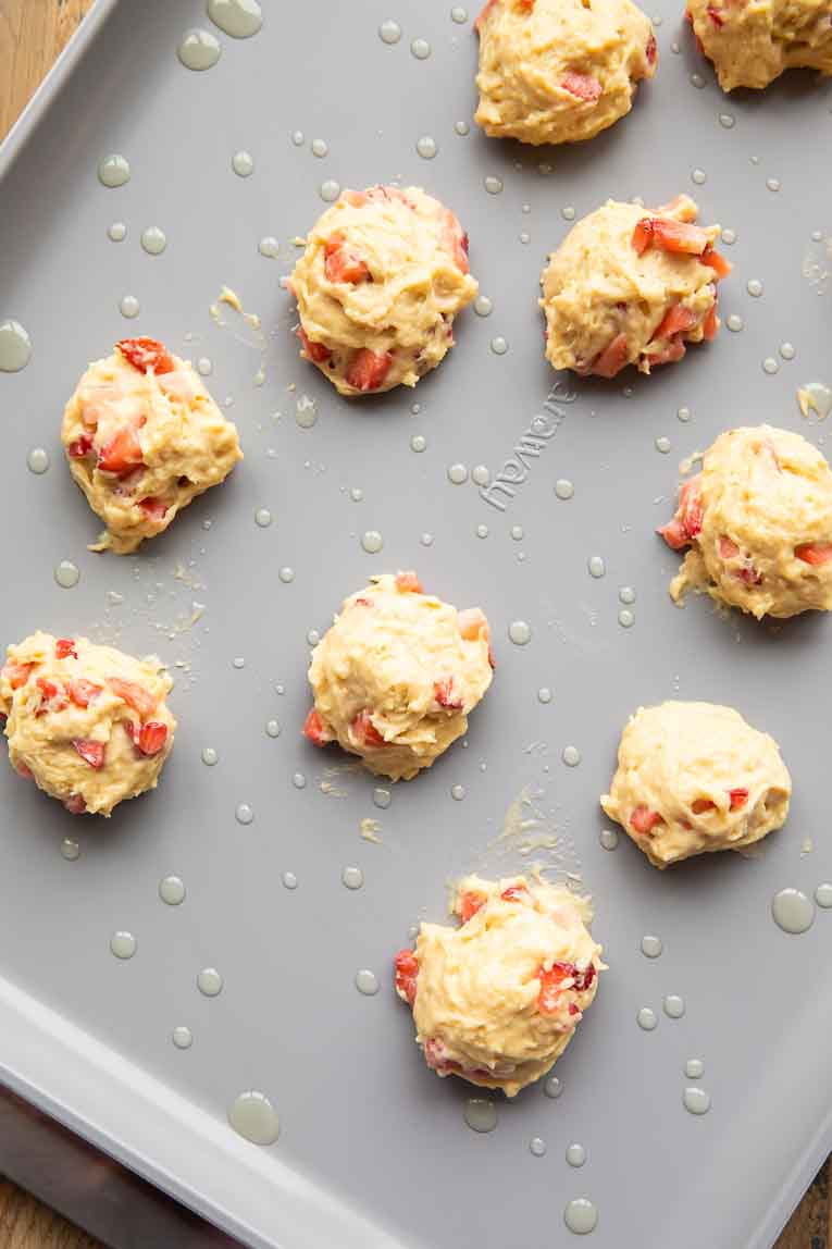Strawberry pancake batter scooped on to a baking sheet.