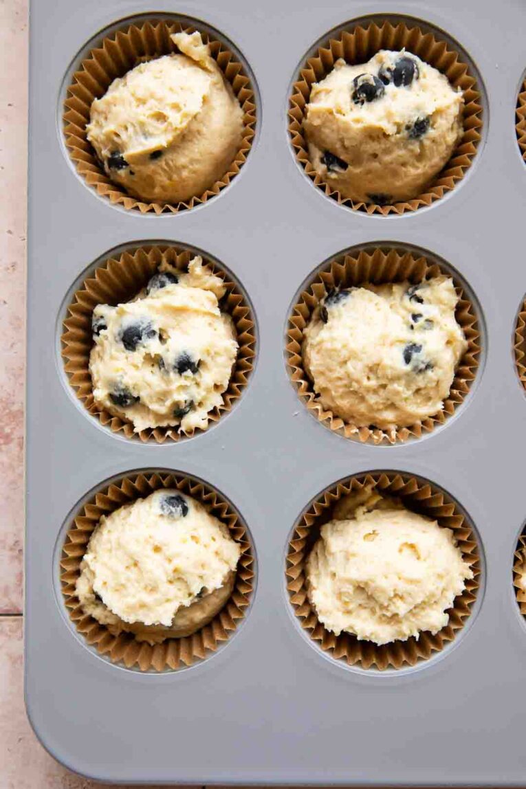 Batter scooped into muffin in for Lemon Blueberry Muffins.