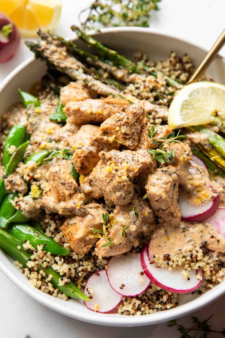 Lemon pepper chicken in a bowl with veggies and quinoa.
