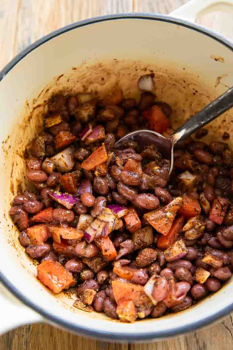 Beans with seasoning being warmed in a pot.