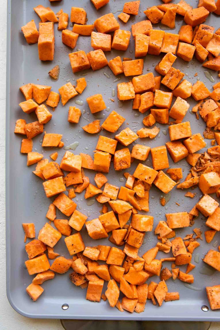 Sweet potatoes roasting on a sheet pan.
