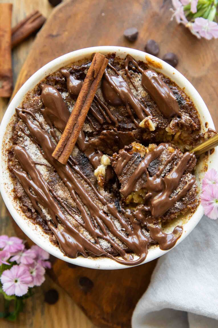Photo of Churro Cheesecake Baked Oats with spoonful taken out and cinnamon chocolate.