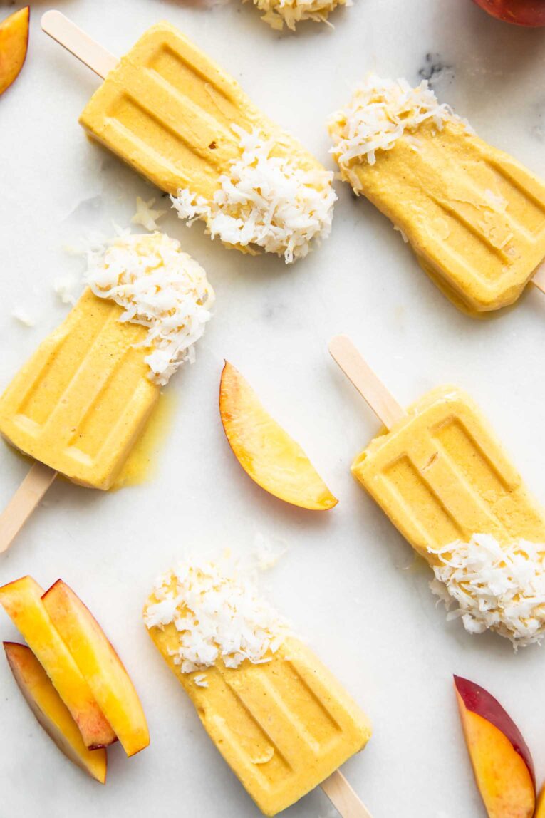 Coconut Peach Popsicles with shredded coconut.