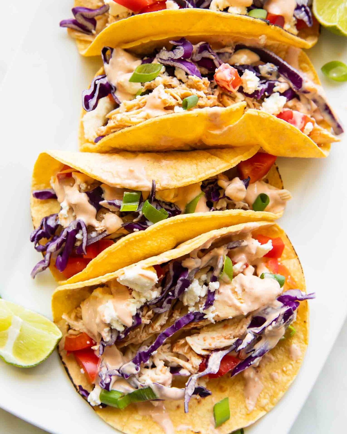 Close up of shredded chicken tacos on a serving platter.