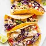 Close up of shredded chicken tacos on a serving platter.
