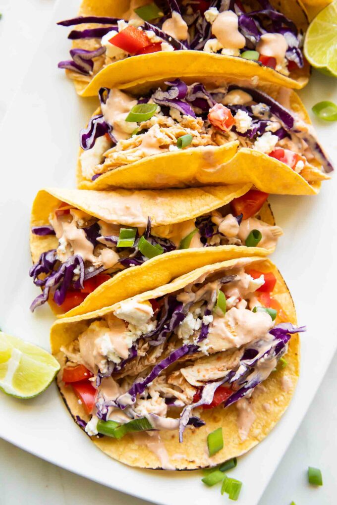 Close up of shredded chicken tacos on a serving platter.