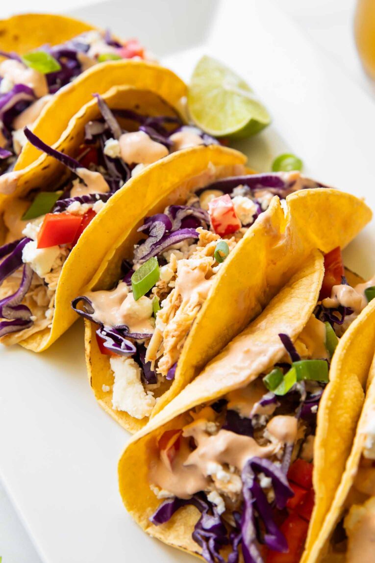 Angled photo of healthy shredded chicken tacos with toppings.