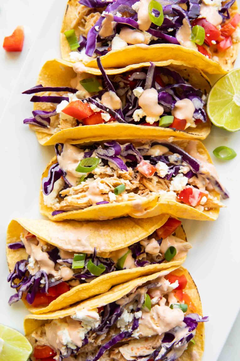 Close up of healthy sriracha shredded chicken tacos with toppings and lime.