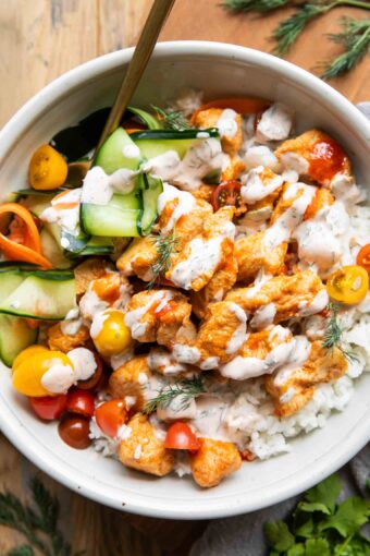 Close up of Sriracha Ranch Chicken in a bowl with rice and pickled veggies.