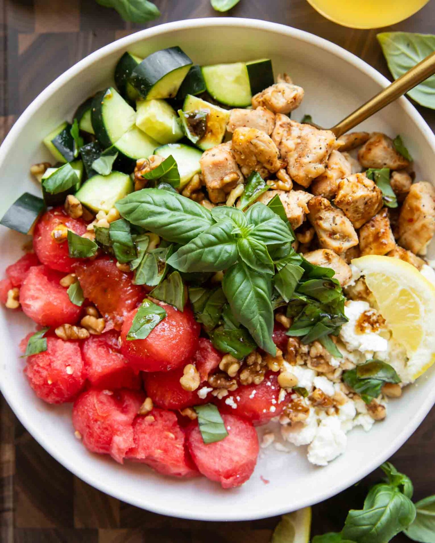 Watermelon Feta Chicken Salad in a bowl with a fork and basil.