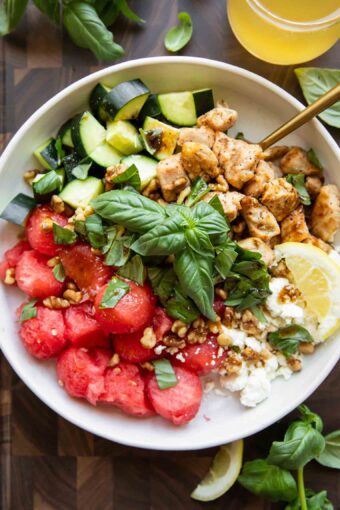 Watermelon Feta Chicken Salad in a bowl with a fork and basil.