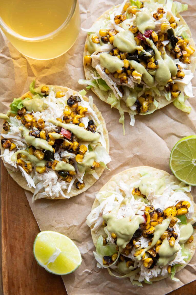 Street Corn Chicken Tostadas with a drink and fresh limes.