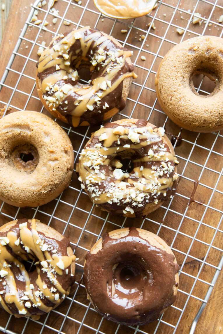 Peanut Butter Chocolate Healthy Donuts on a cooling rack with toppings.