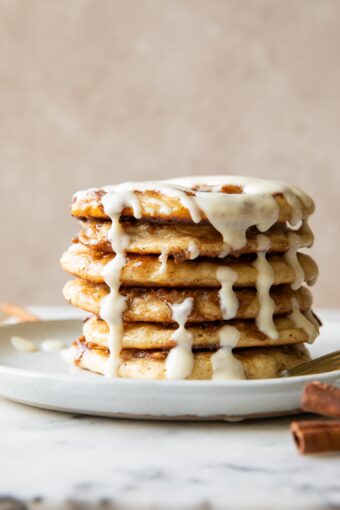 A stack of cinnamon roll pancakes on a plate.