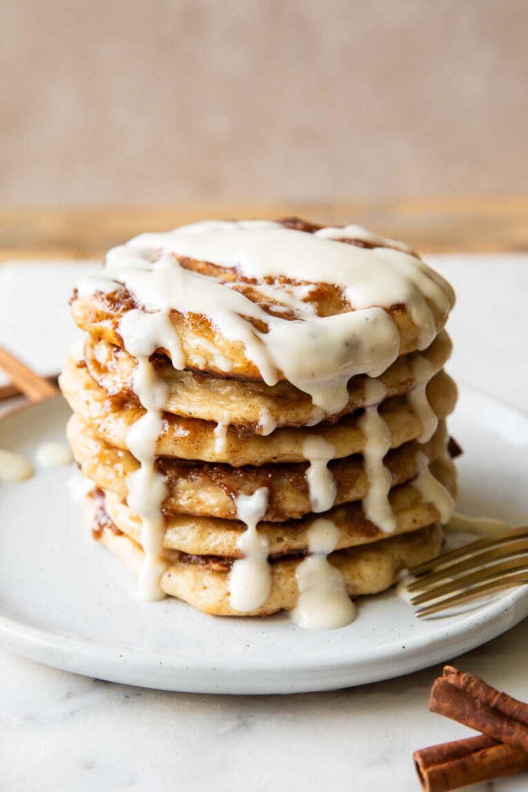Angled view of A stack of cinnamon roll pancakes on a plate.
