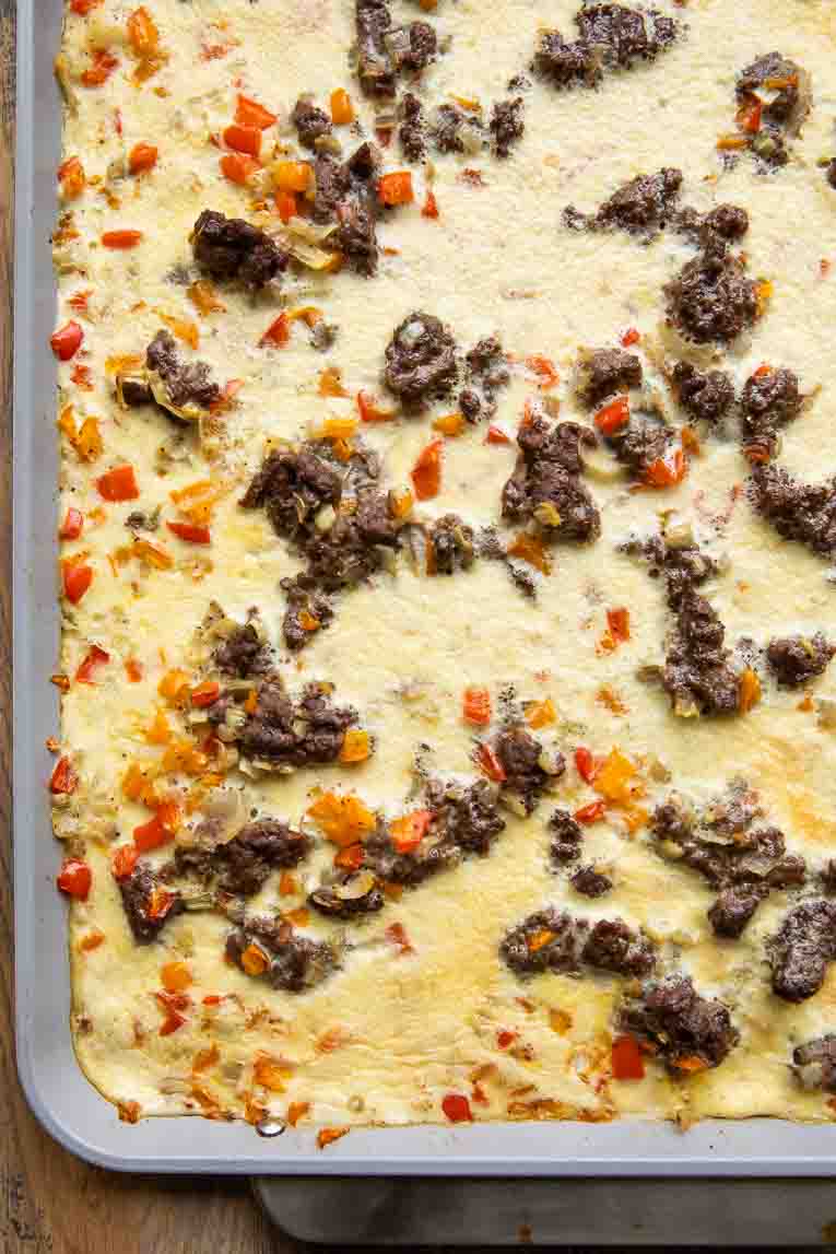 Cooked eggs, sausage, and peppers on a sheet pan.