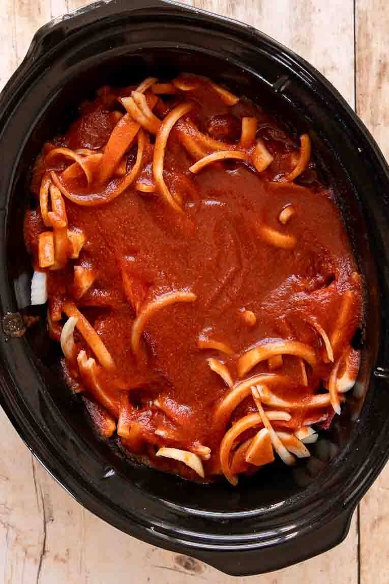 Ribs, sauce, and onions in a crockpot.