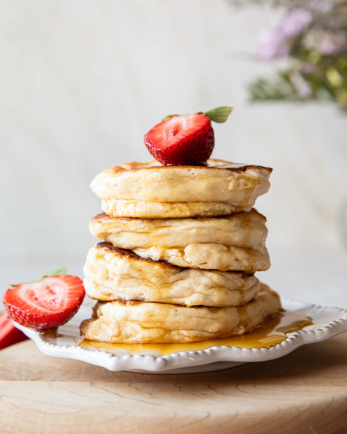 A stack of Souffle Pancakes on a plate topped with a strawberry.