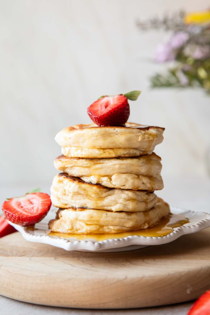 A stack of Souffle Pancakes on a plate topped with a strawberry.